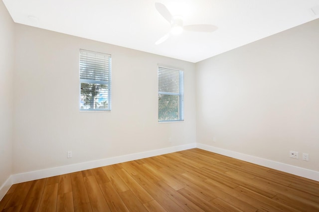 empty room featuring a ceiling fan, baseboards, and wood finished floors