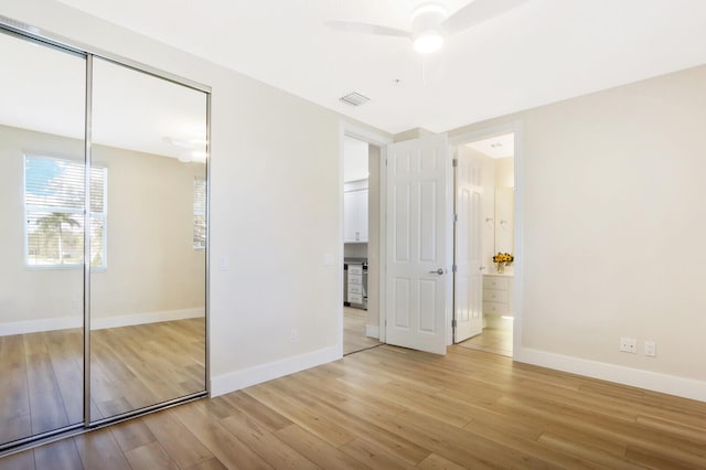 unfurnished bedroom with light wood finished floors, a closet, connected bathroom, and baseboards