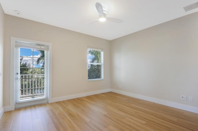 unfurnished room featuring a wealth of natural light, baseboards, visible vents, and light wood finished floors