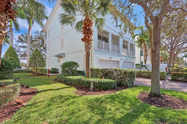 view of side of property with a garage, a lawn, and a balcony