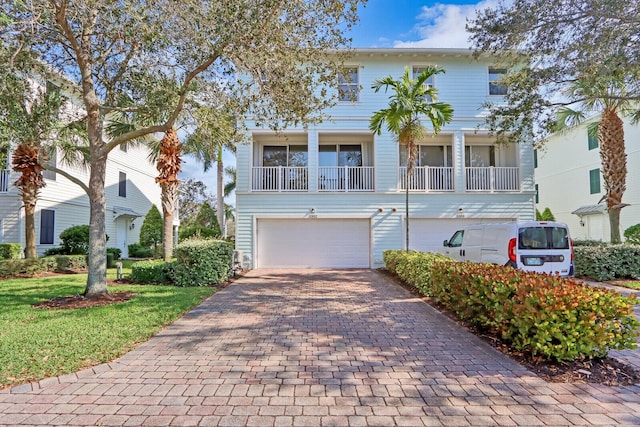 view of front facade with a garage, decorative driveway, and a balcony