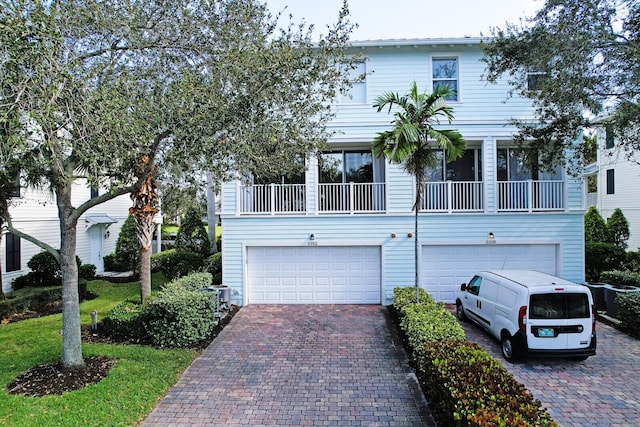 view of property featuring a garage, decorative driveway, and a balcony