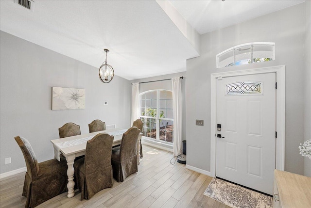 dining room featuring light wood finished floors, visible vents, baseboards, and an inviting chandelier