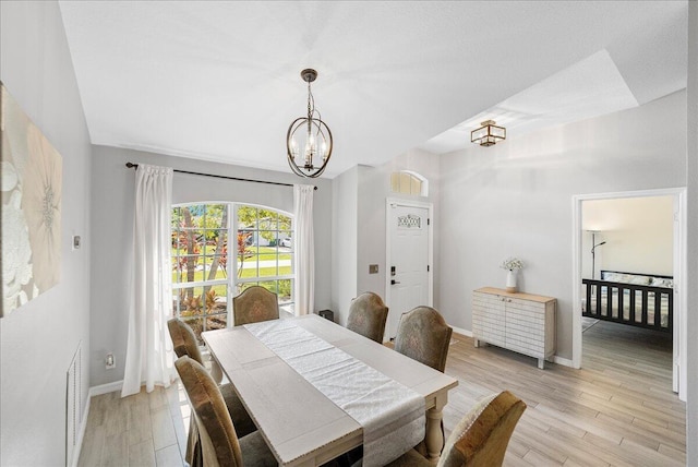 dining area featuring a chandelier, baseboards, visible vents, and light wood finished floors