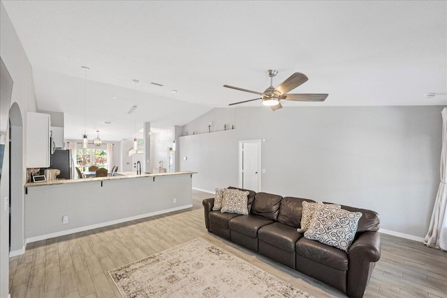 living area featuring light wood-type flooring, ceiling fan, baseboards, and lofted ceiling