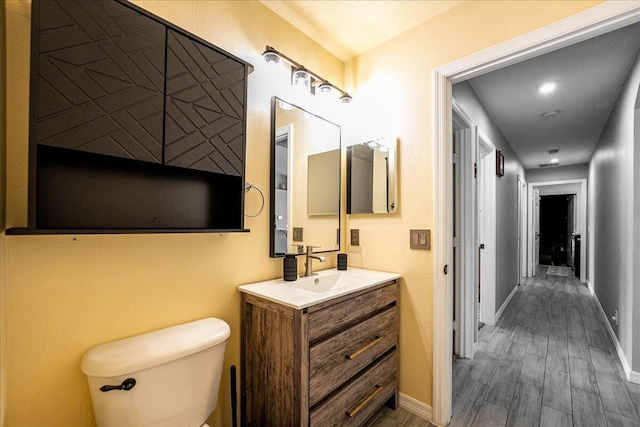 bathroom featuring vanity, wood finished floors, toilet, and baseboards