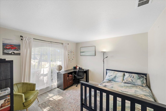 bedroom featuring a textured ceiling, light wood finished floors, and visible vents