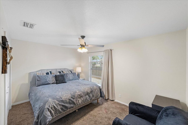 carpeted bedroom with a ceiling fan, visible vents, a textured ceiling, and baseboards