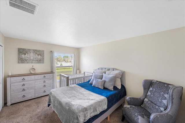 carpeted bedroom featuring a textured ceiling and visible vents