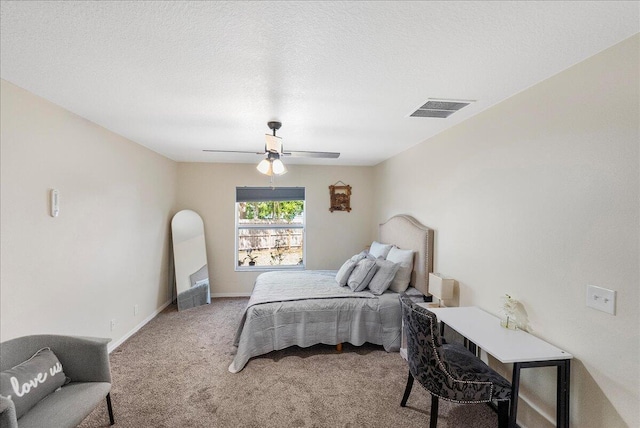 carpeted bedroom with baseboards, a textured ceiling, visible vents, and a ceiling fan