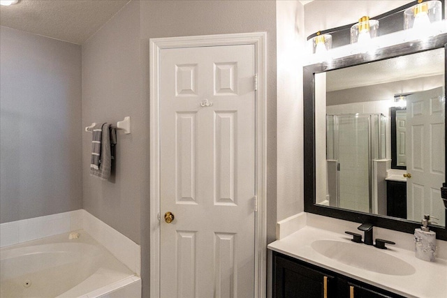 bathroom with a stall shower, a tub with jets, and vanity