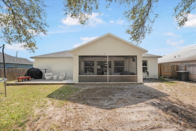 rear view of house with a sunroom, a patio area, a fenced backyard, and stucco siding