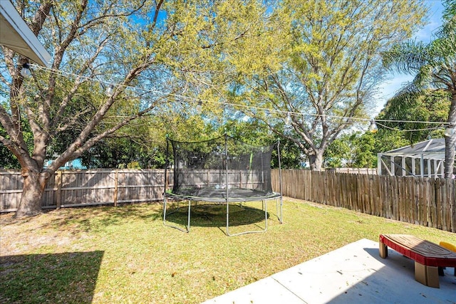 view of yard featuring a trampoline, a patio area, and a fenced backyard