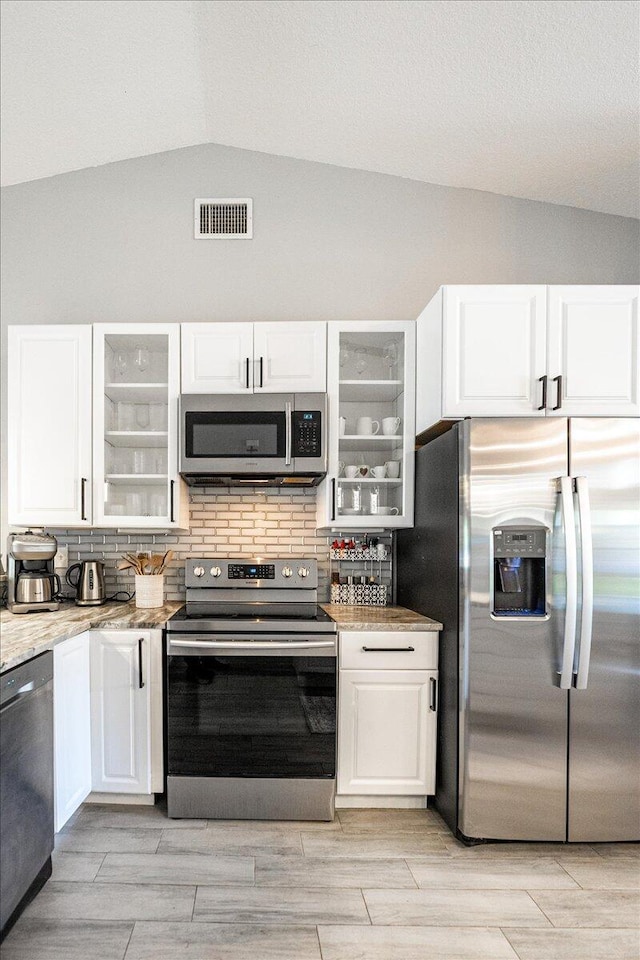 kitchen featuring appliances with stainless steel finishes, visible vents, glass insert cabinets, and white cabinetry