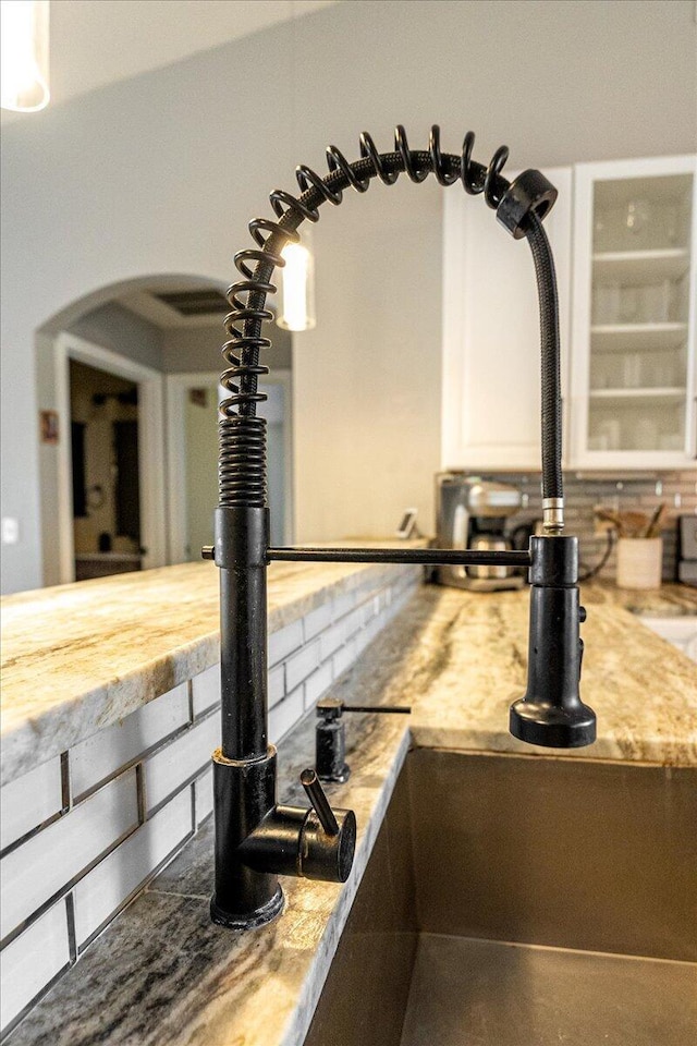 interior details featuring arched walkways, light countertops, a sink, and white cabinetry