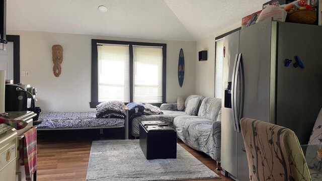 bedroom featuring lofted ceiling, dark wood-style floors, stainless steel fridge, and a textured ceiling