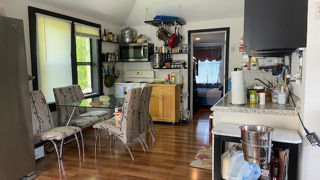 kitchen featuring light brown cabinets, stainless steel appliances, vaulted ceiling, light countertops, and dark wood finished floors