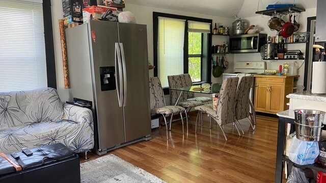 kitchen featuring vaulted ceiling, appliances with stainless steel finishes, light countertops, and wood finished floors