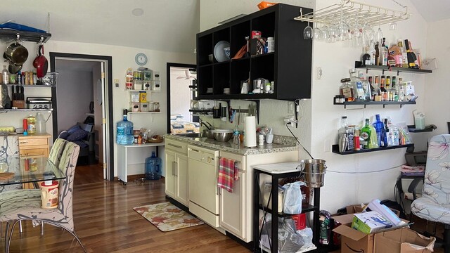 kitchen featuring light stone counters, white dishwasher, dark wood-style flooring, a sink, and open shelves