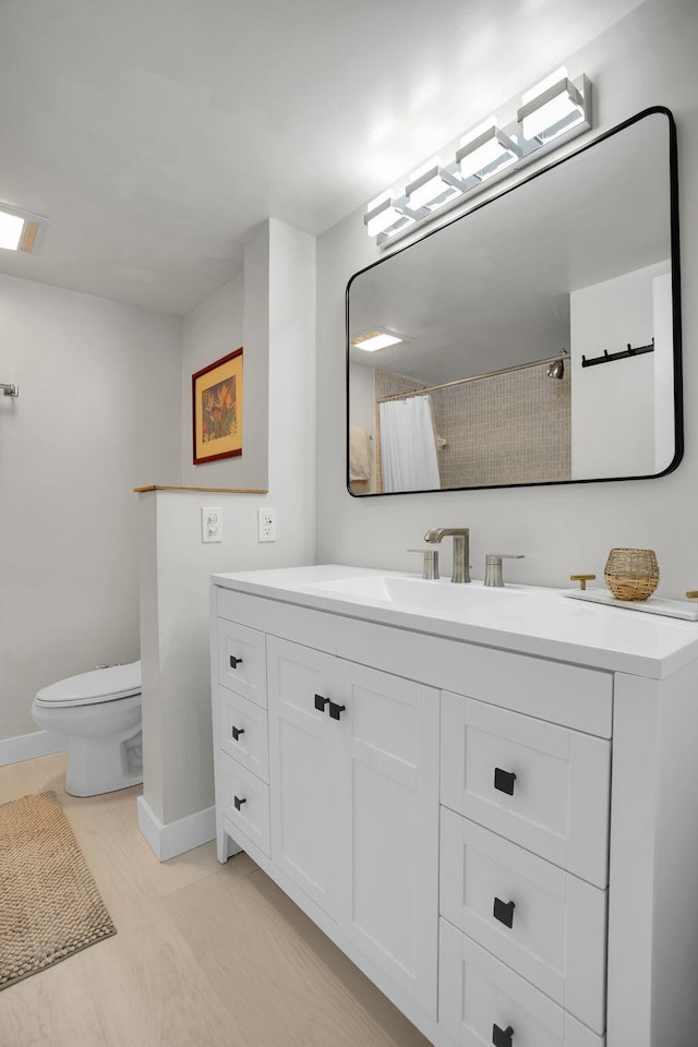 bathroom with toilet, a shower with shower curtain, wood finished floors, vanity, and baseboards