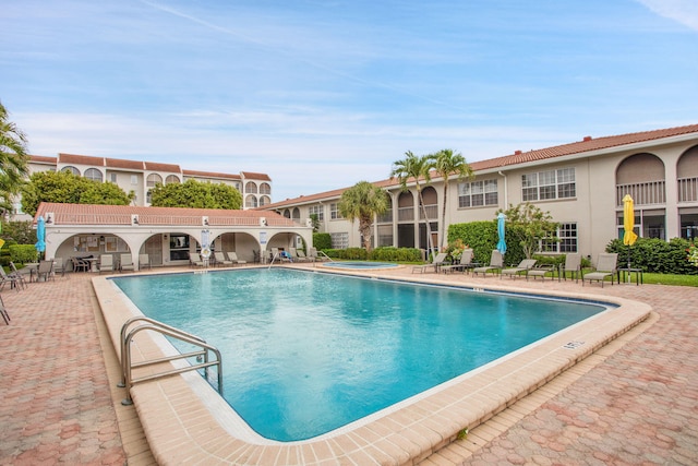 pool with a community hot tub and a patio