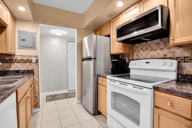 kitchen featuring light brown cabinets, stainless steel appliances, a sink, electric panel, and dark countertops