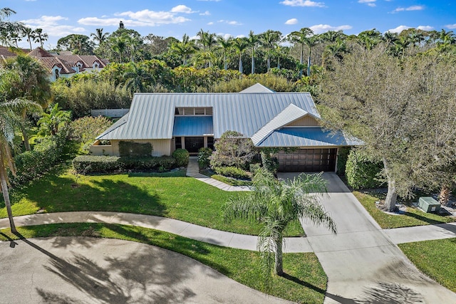 view of front facade featuring metal roof, concrete driveway, a front lawn, and a garage