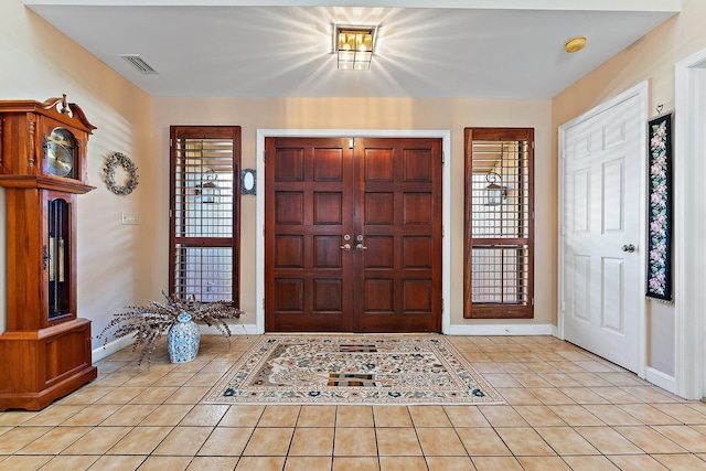 foyer featuring light tile patterned floors, plenty of natural light, visible vents, and baseboards