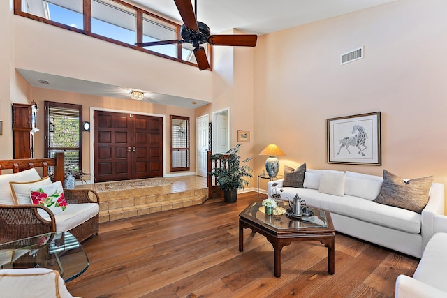 living room featuring baseboards, visible vents, a ceiling fan, and dark wood-style flooring