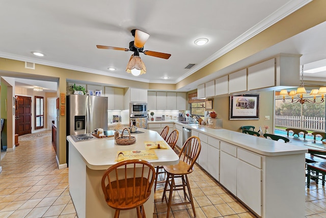 kitchen featuring white cabinetry, light countertops, appliances with stainless steel finishes, a center island, and crown molding