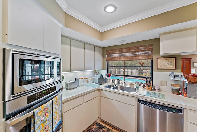 kitchen featuring light countertops, appliances with stainless steel finishes, a sink, and white cabinetry