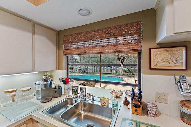 kitchen with white cabinetry, light countertops, and a sink