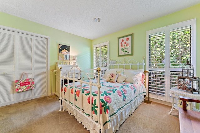 bedroom with a closet, light colored carpet, and a textured ceiling