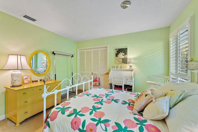 bedroom with carpet floors, a closet, visible vents, and a textured ceiling