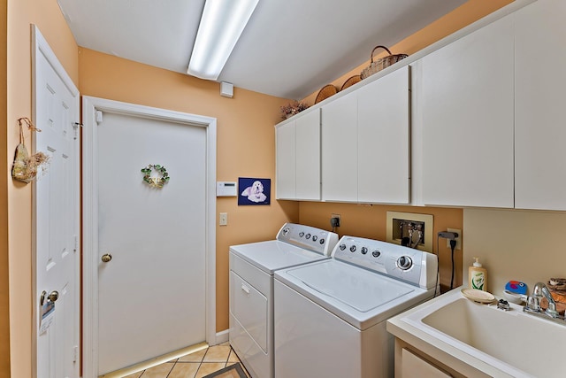 clothes washing area featuring cabinet space, washing machine and dryer, a sink, and light tile patterned flooring