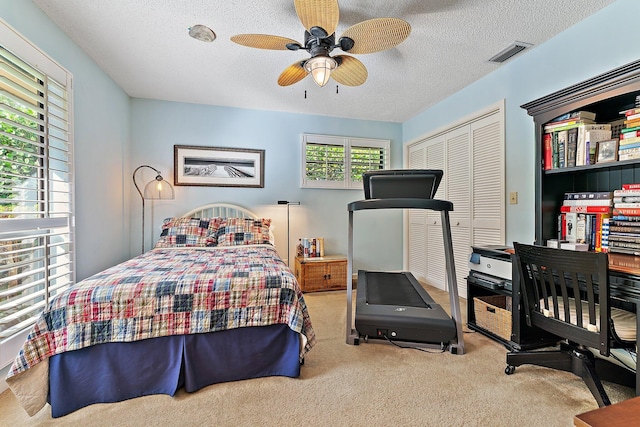 bedroom featuring light colored carpet, visible vents, and a textured ceiling