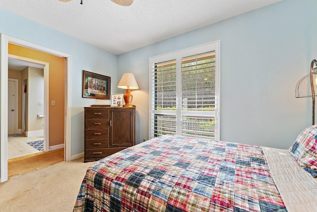 bedroom with baseboards, a textured ceiling, and light colored carpet