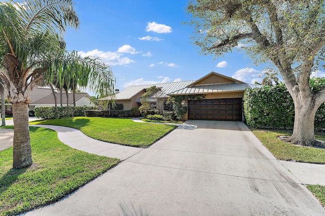 view of front of home featuring metal roof, an attached garage, driveway, a front lawn, and a standing seam roof