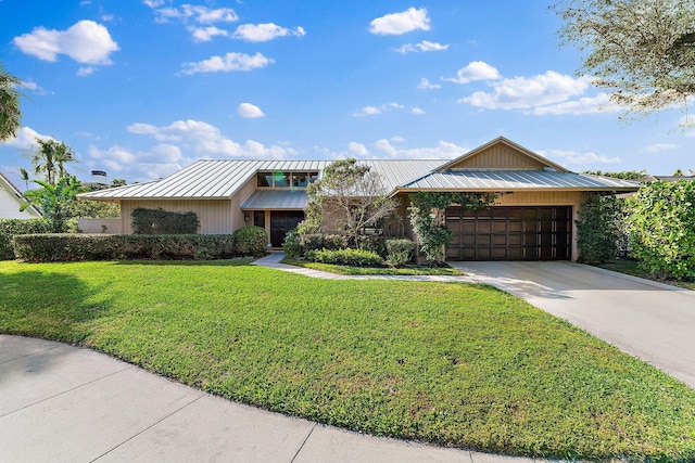 mid-century inspired home with metal roof, a garage, driveway, a front lawn, and a standing seam roof