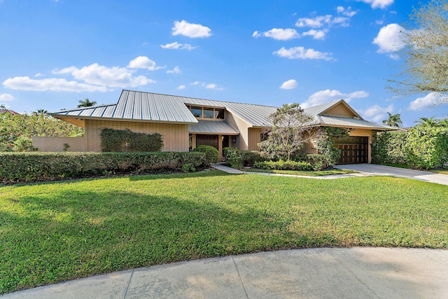 view of front of home with a garage, concrete driveway, metal roof, a standing seam roof, and a front yard