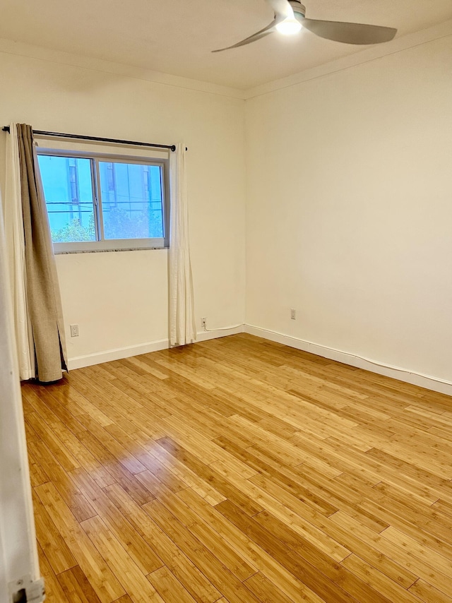 spare room featuring light wood-type flooring, crown molding, baseboards, and ceiling fan