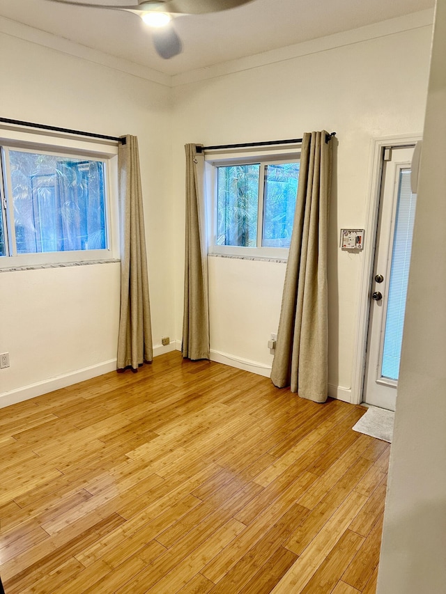 unfurnished bedroom with light wood-type flooring, crown molding, baseboards, and ceiling fan