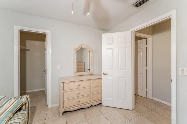 bedroom featuring a walk in closet, visible vents, baseboards, and light tile patterned flooring