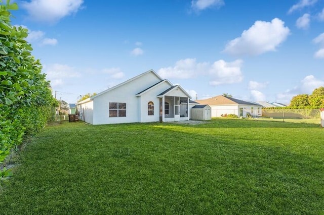 rear view of property featuring a yard, a fenced backyard, an outdoor structure, and a shed