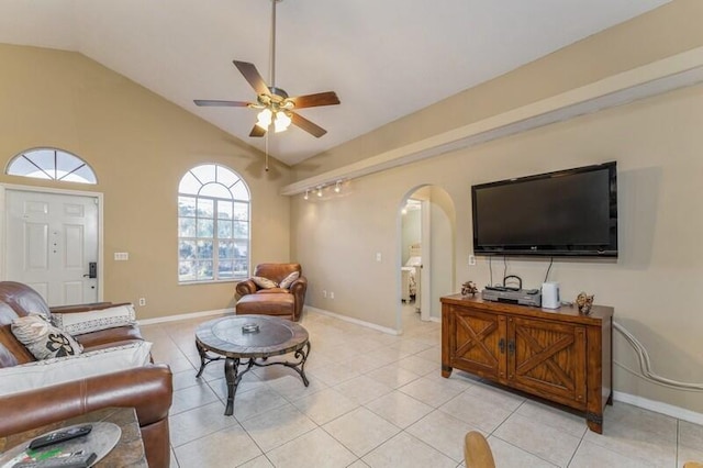 living room with arched walkways, light tile patterned floors, ceiling fan, vaulted ceiling, and baseboards