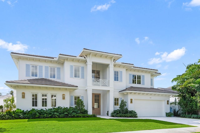 view of front of house with a tile roof, stucco siding, concrete driveway, a front yard, and a garage