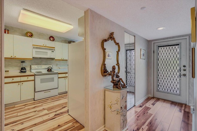 kitchen with white appliances, light countertops, a textured ceiling, and light wood finished floors