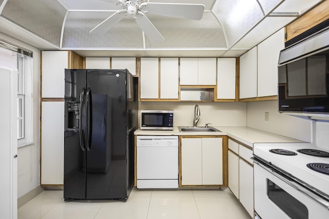 kitchen featuring light tile patterned floors, light countertops, white cabinetry, a sink, and white appliances