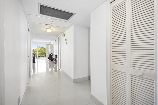 hallway featuring light tile patterned floors, visible vents, and baseboards