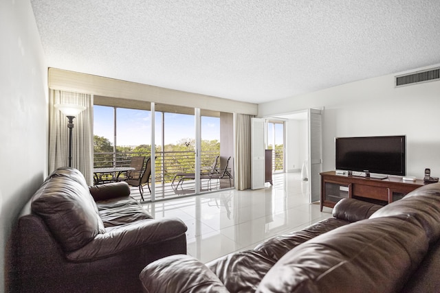 living area with light tile patterned floors, visible vents, and a textured ceiling